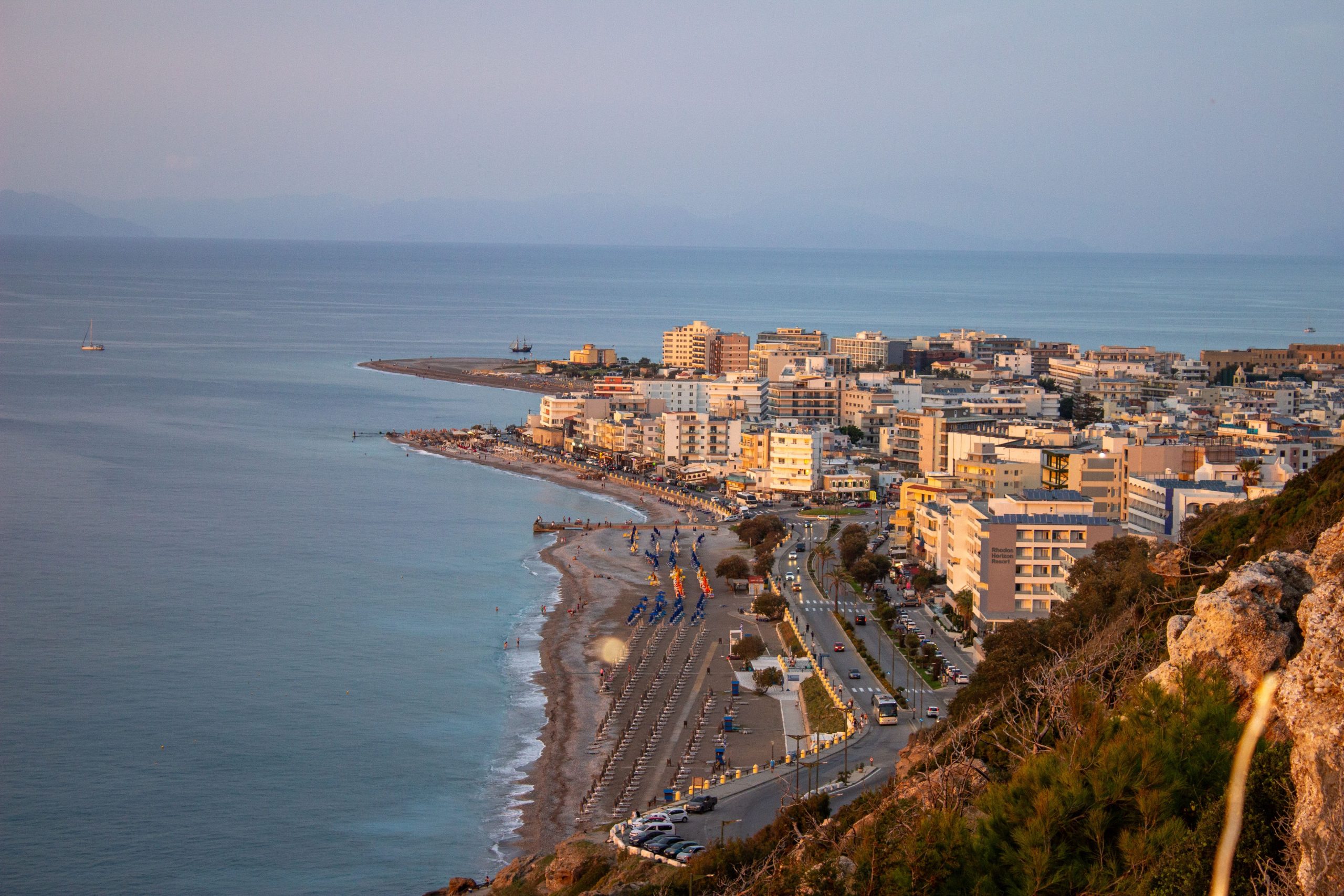 An aerial view of a coastal city with a beautiful sunset over the sea.