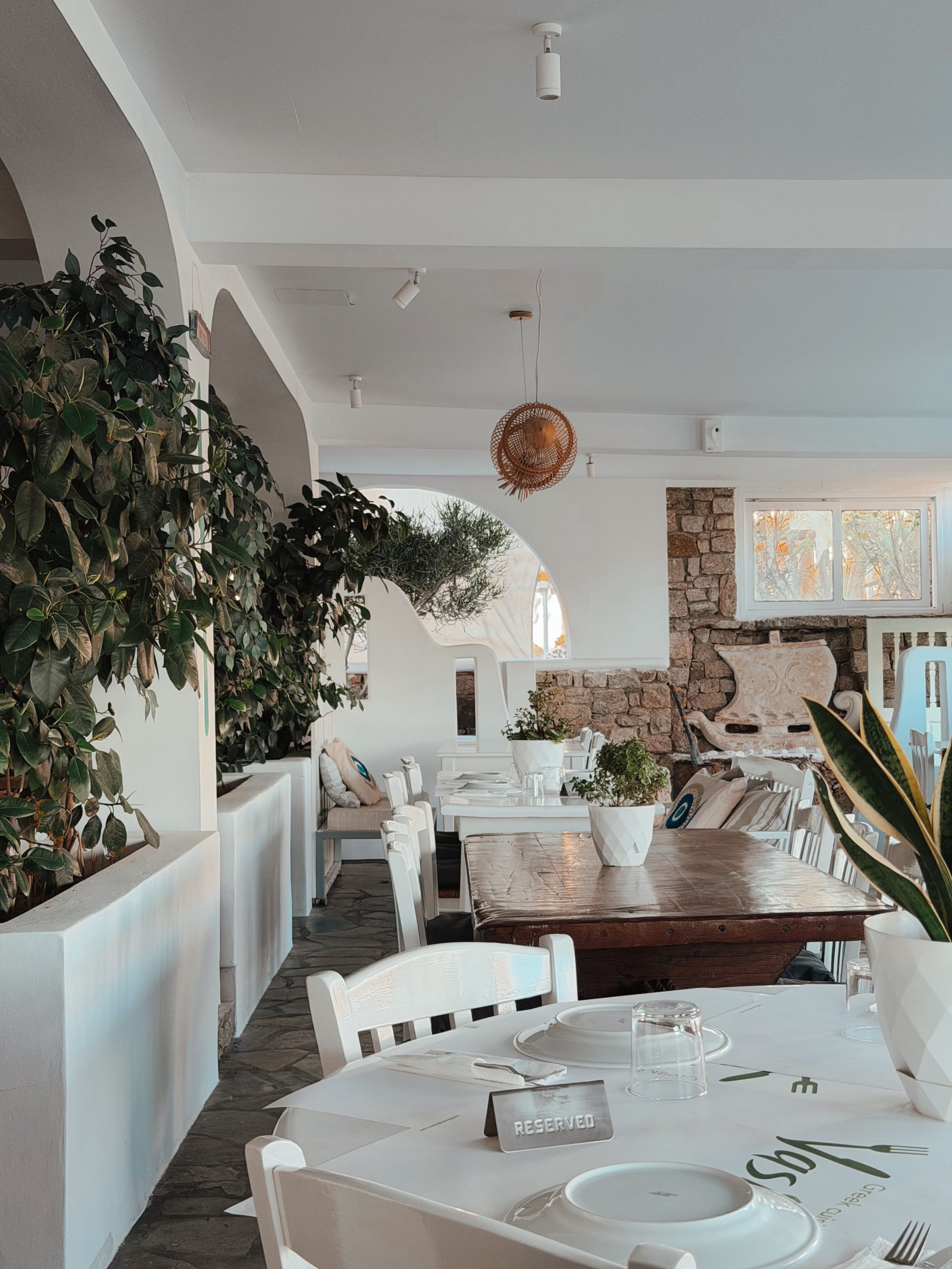 Inviting indoor setting of a Greek restaurant with rustic decor and natural elements.